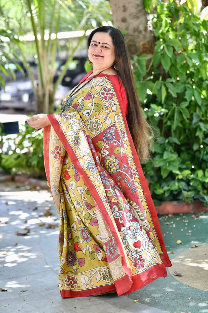 Kawaii kalamkari saree with traditional floral and geometric patterns in red and yellow worn by a woman outdoors